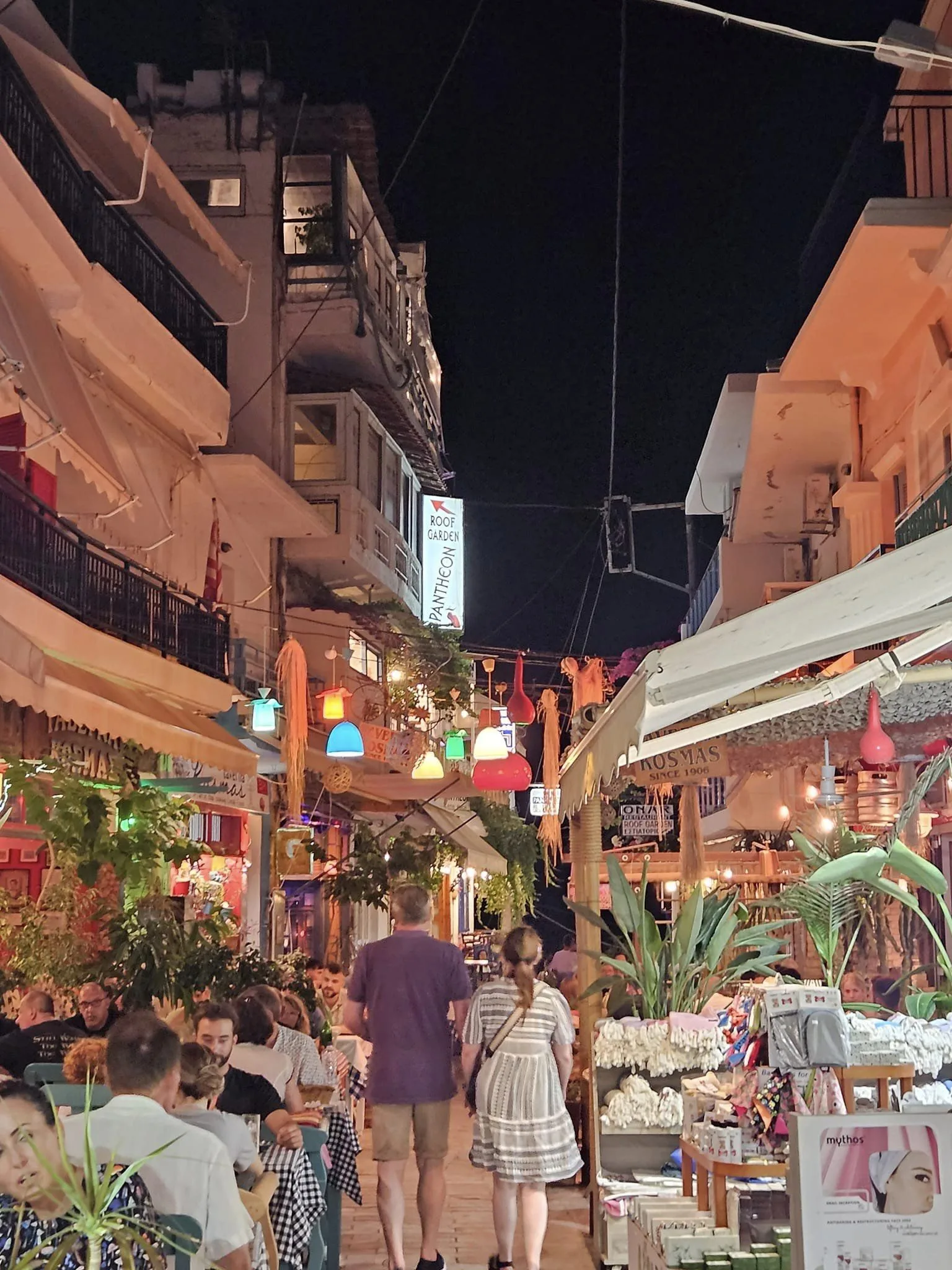 Realisic photo of a street market at night with a lot of shops in left and right of a walkway