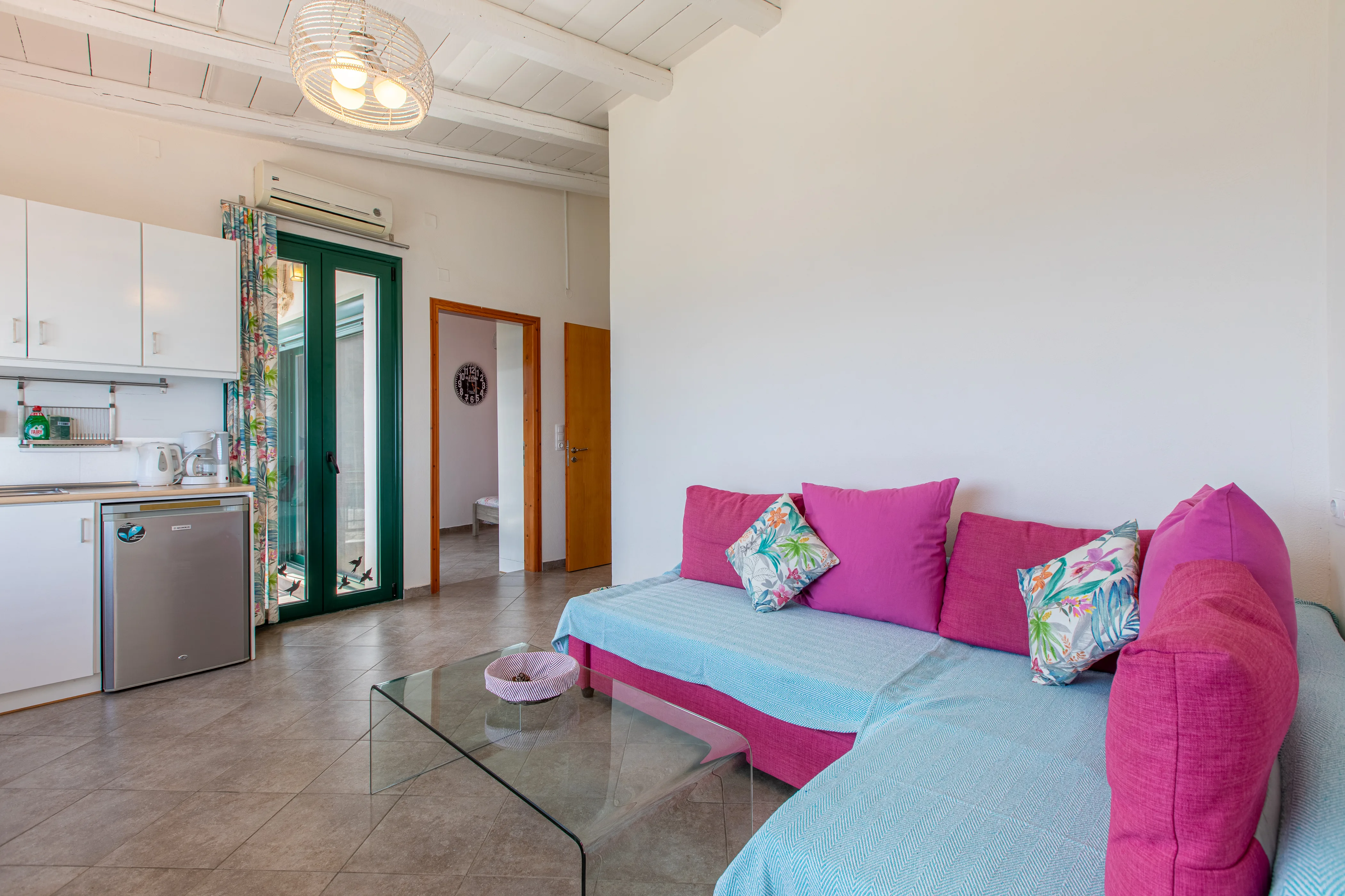 inside view of the apartment room featuring a large sofa and the kitchen in the background
