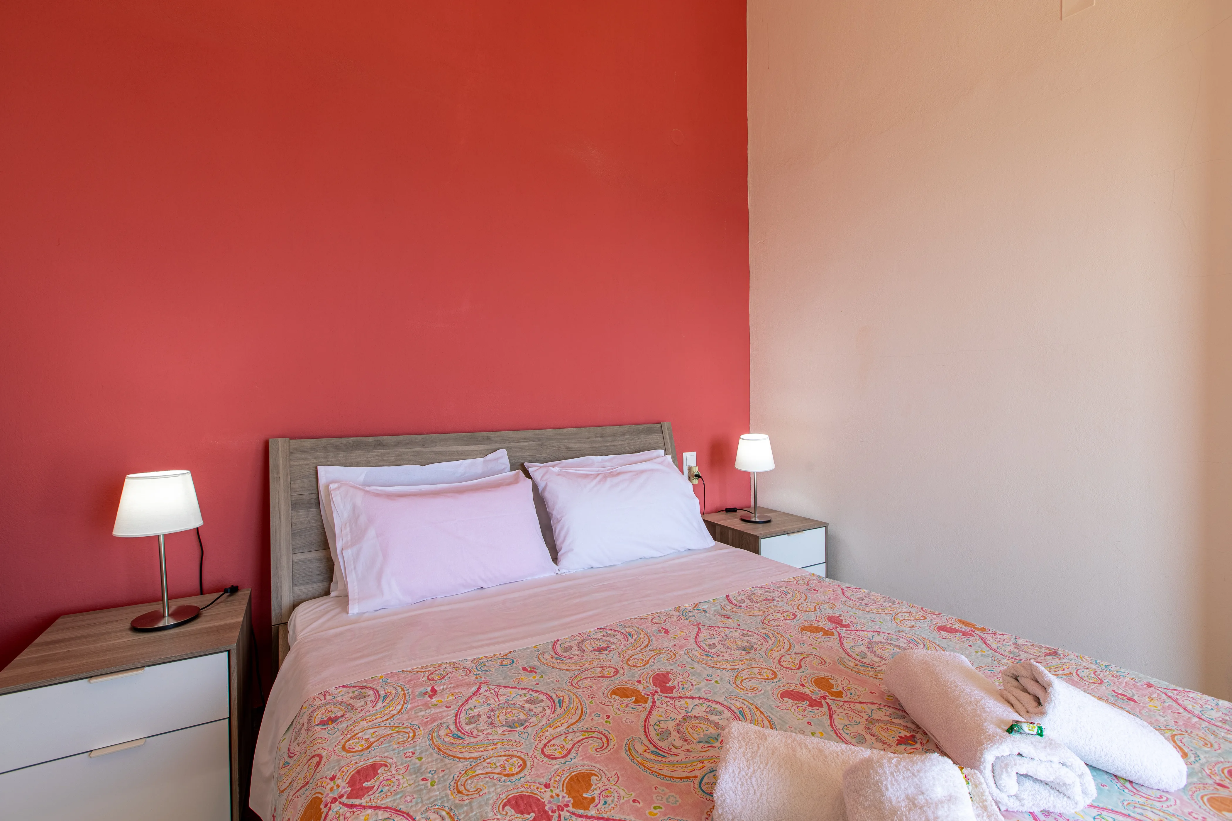 inside view of the apartment room featuring a large double bed with neatly folded towels on it