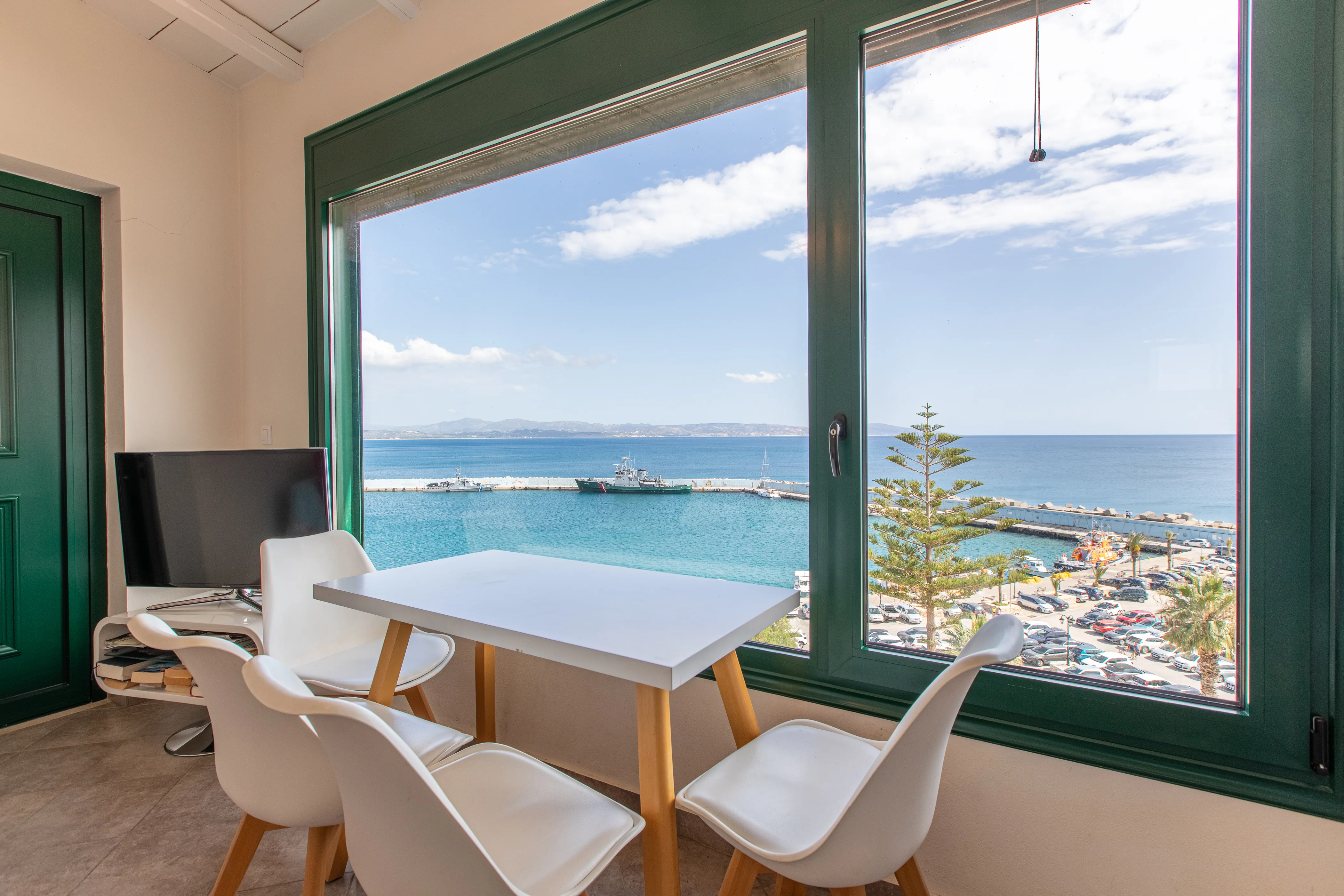inside view of the apartment room featuring the dining table and a large window with clear view of the sea