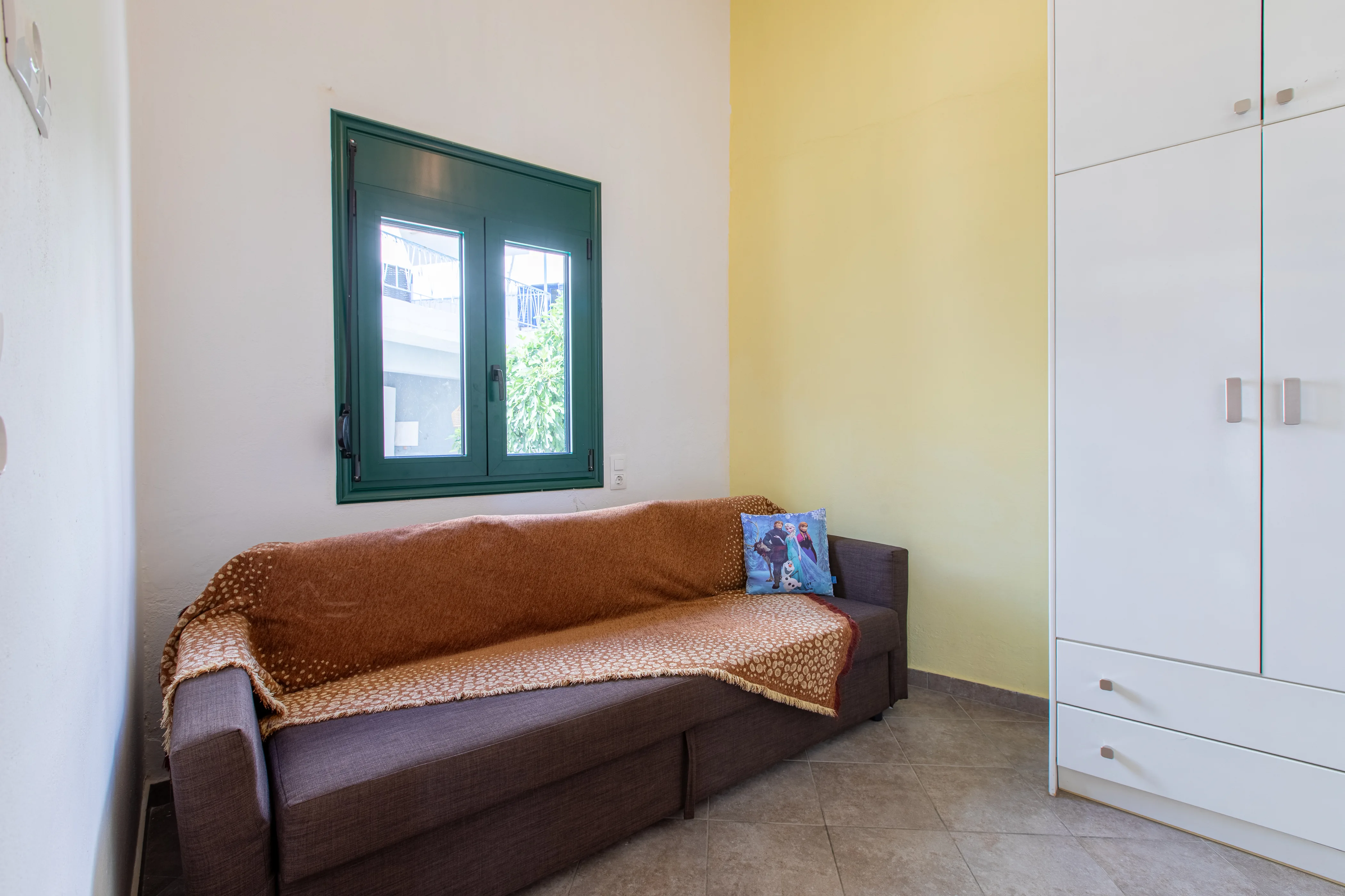inside view of the apartment room featuring a sofa in a closed room with a window above it