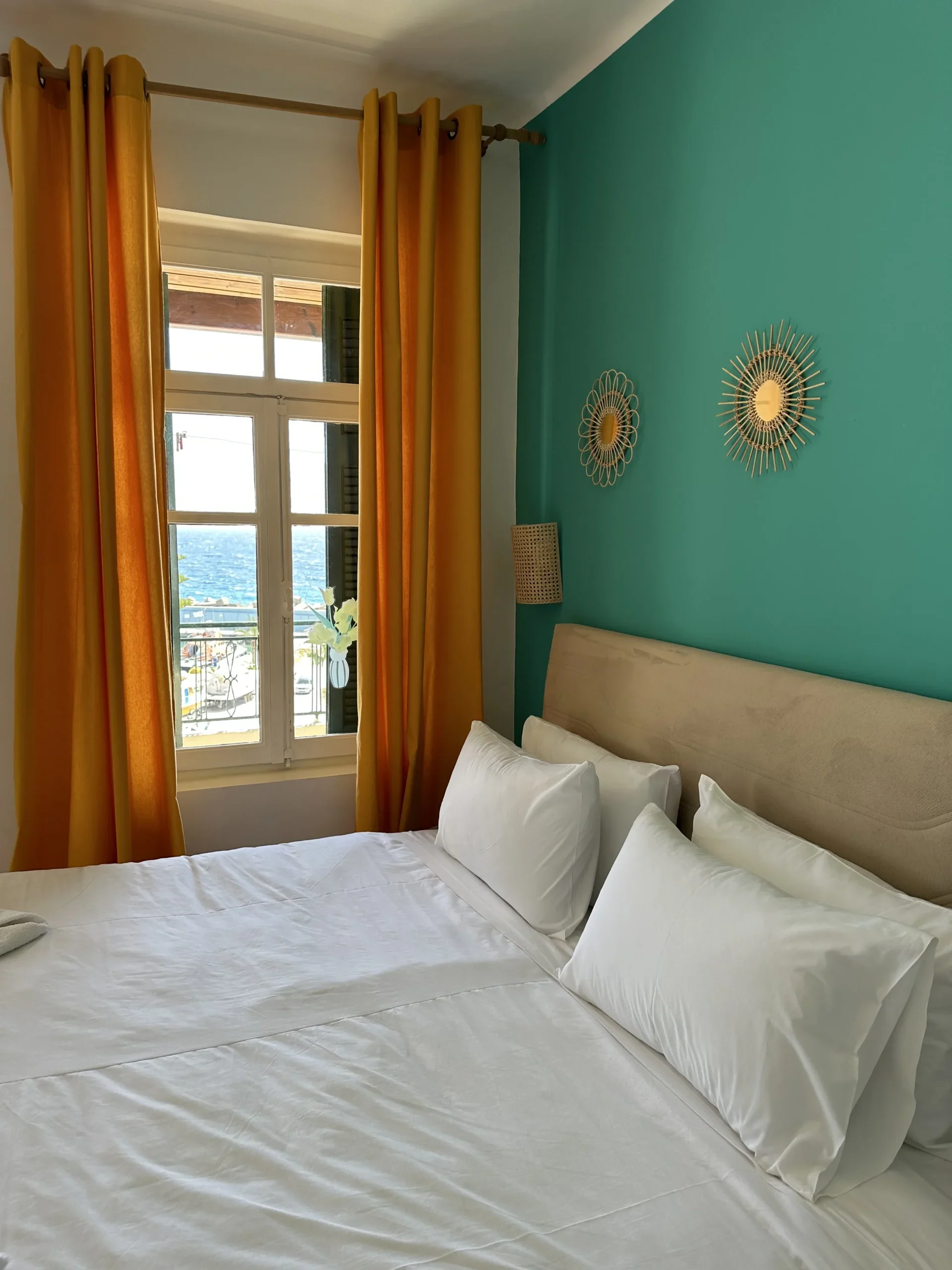 inside view of a room featuring a large double bed with a window next to it and some wall decorations