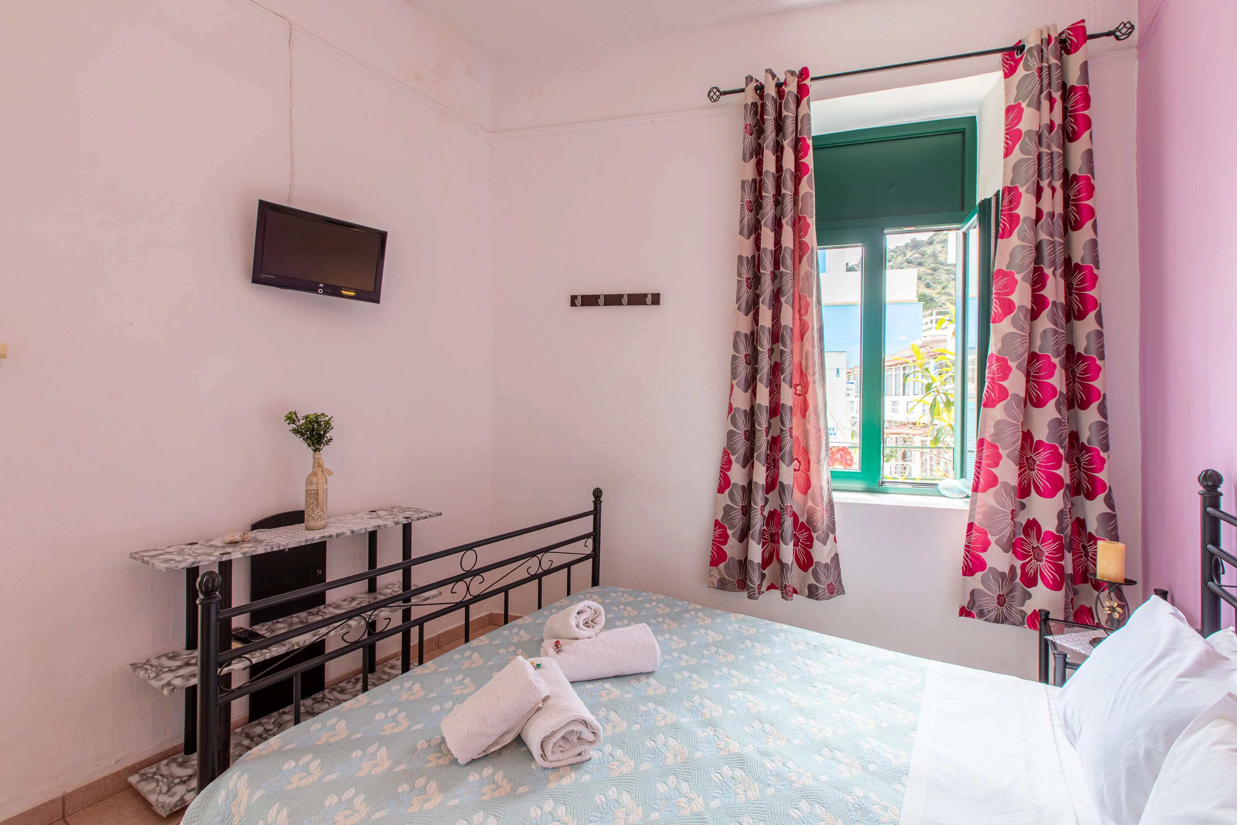 inside view of a room featuring a large double bed with a window next to it