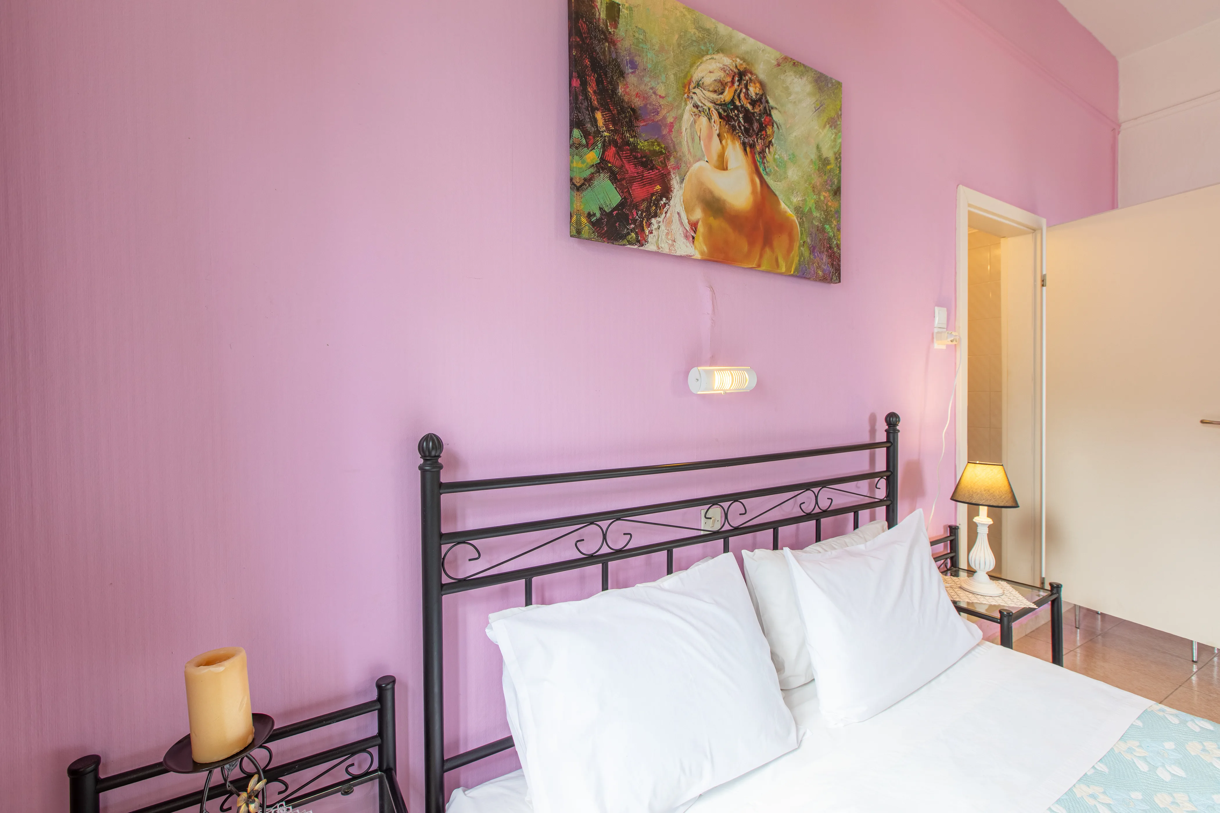 inside view of a room featuring a large double bed with a painting above it on the purple painted wall