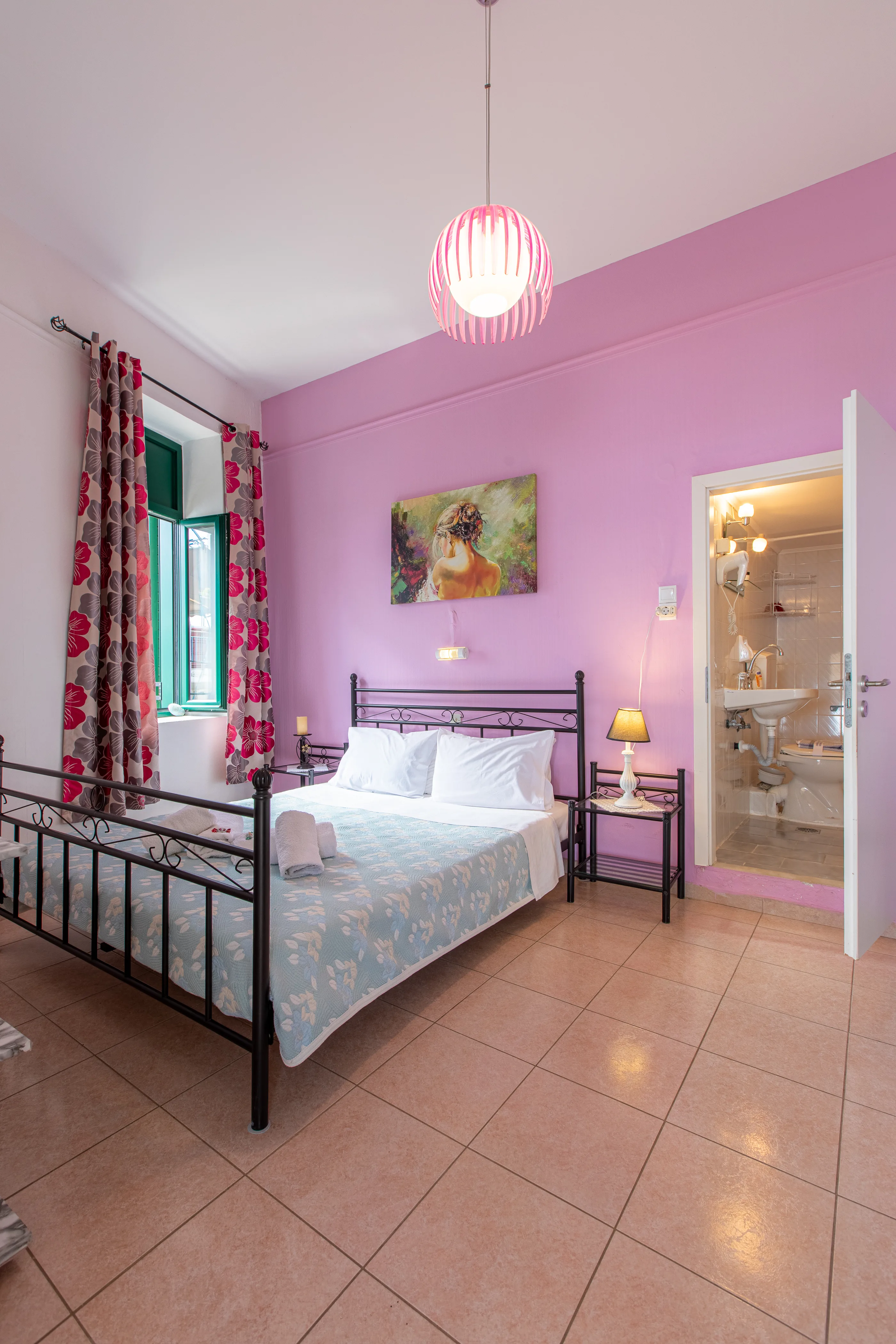 inside view of a room featuring a large double bed with a window next to it and a wall painting above it