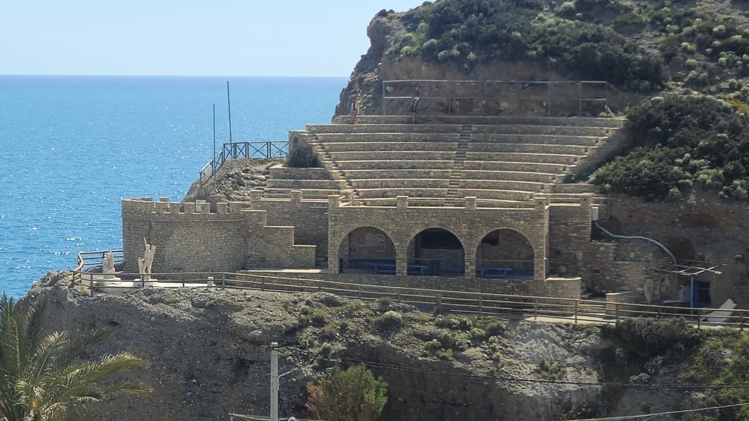 outside view from afar of a old stone amphitheater on a cliff