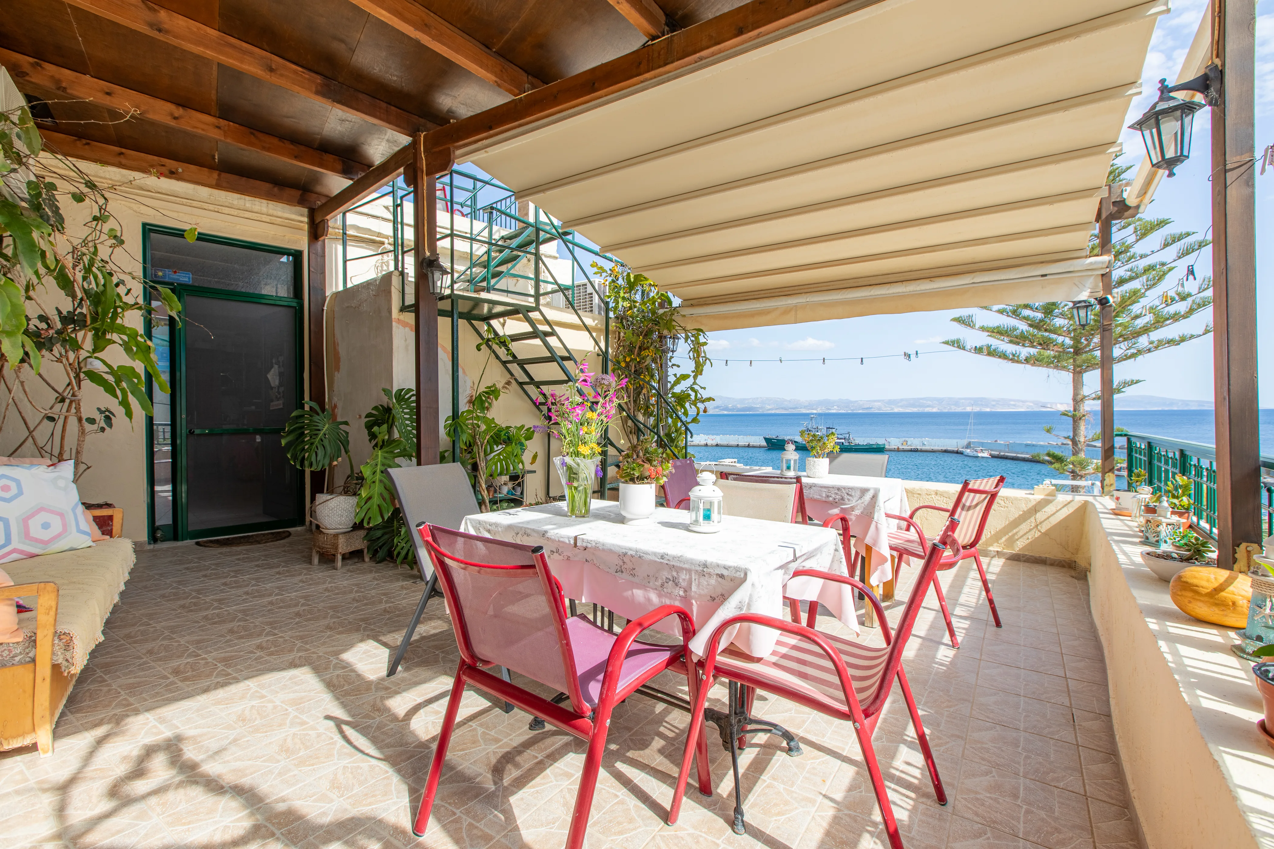 outside view of a balcony featuring dining tables and a lot of plants spread around