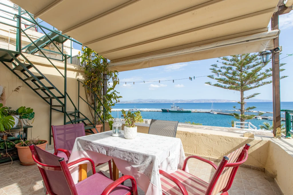 outside view of a balcony featuring a dining table and a metallic ladder on the side going on an upper floor