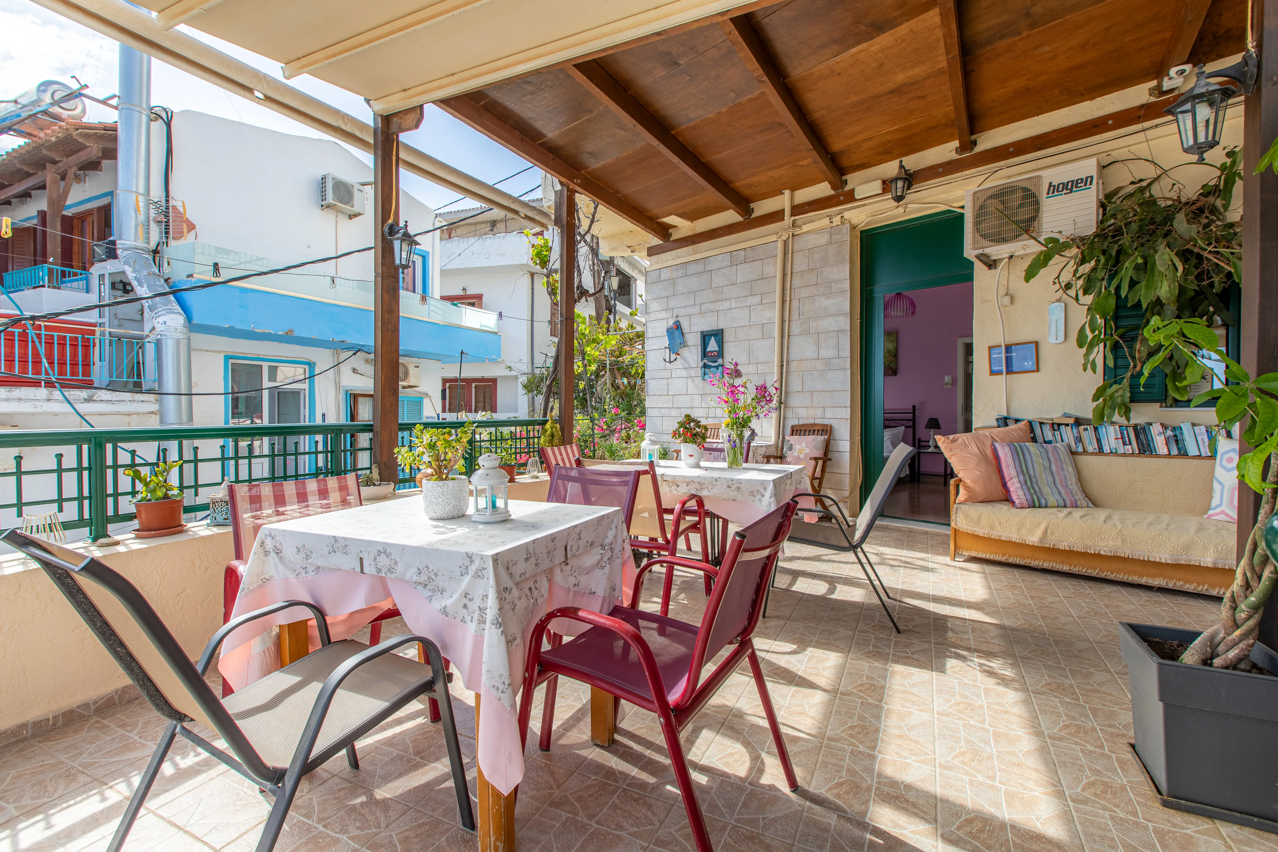 outside view of a balcony featuring dining tables and a lot of plants spread around and a open door in the background leading to a hotel room