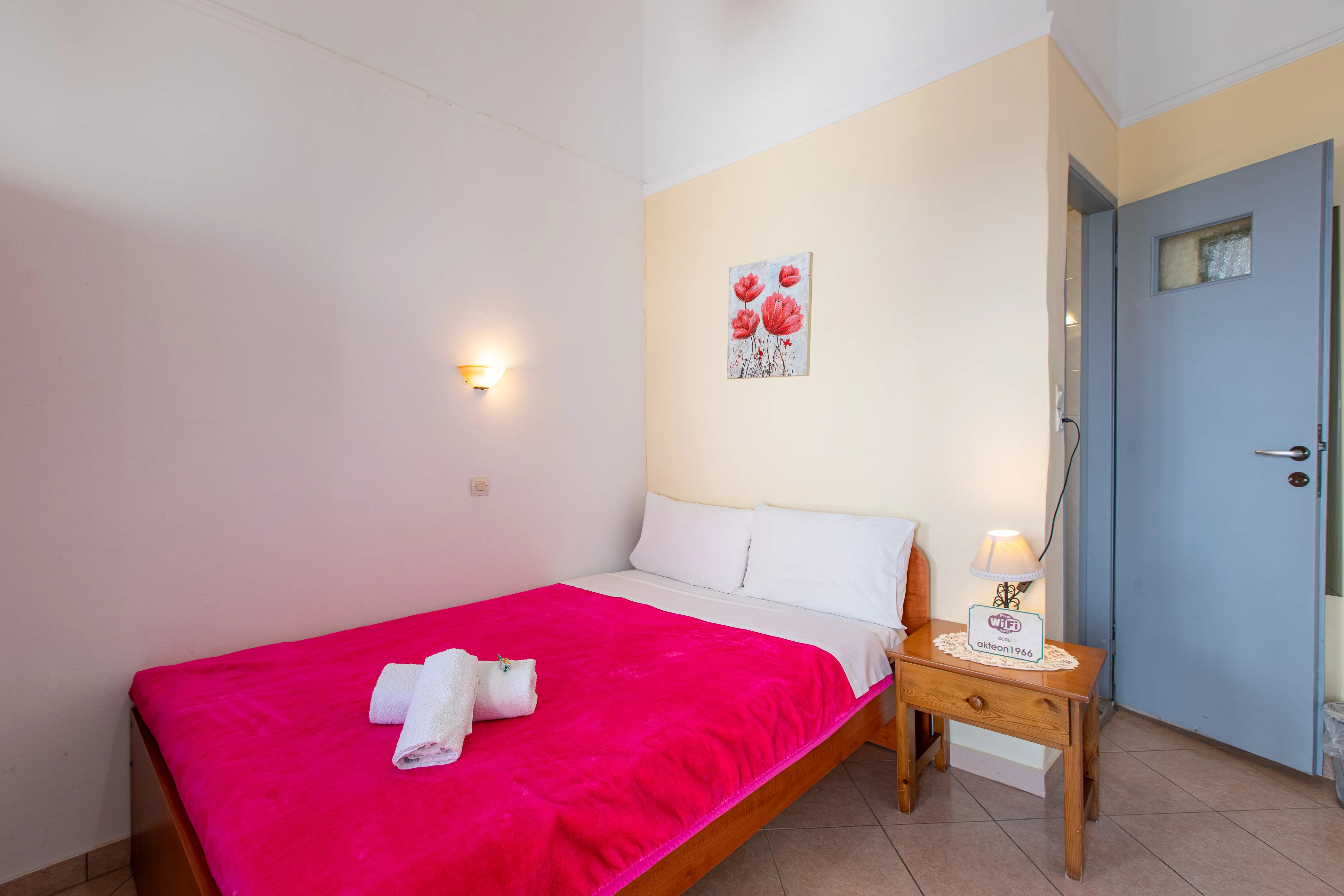 inside view of a room featuring a double bed with red bedsheets and wall decorations