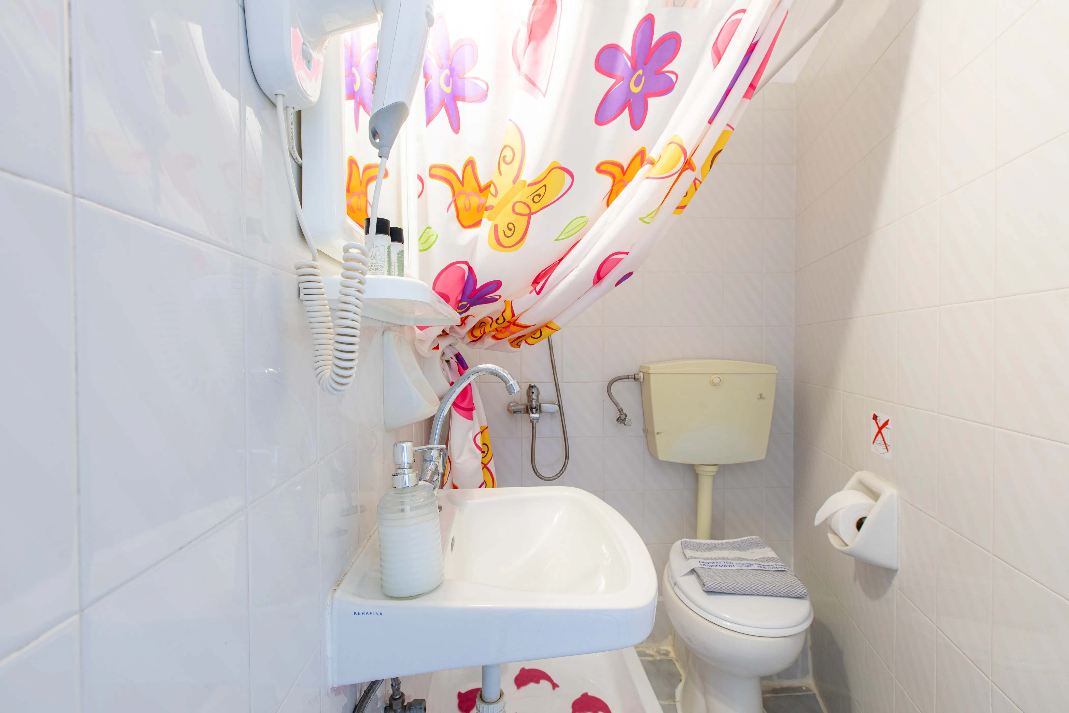 inside view of bathroom with a sink , toilet and a shower area with a colorful curtain