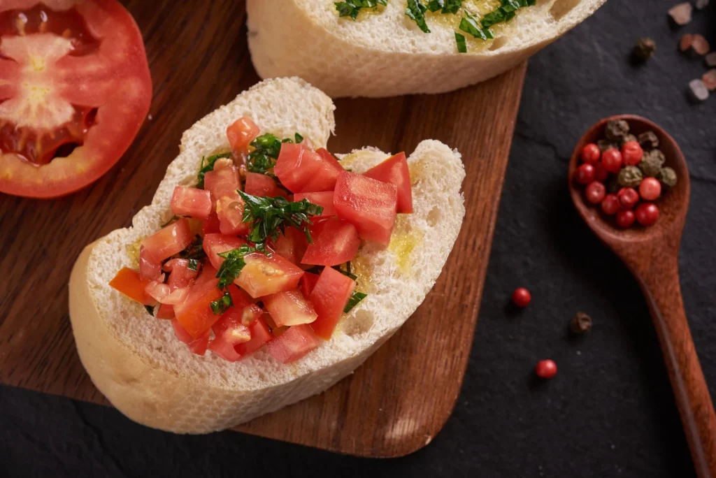 Close up photo of a bread with olive oil and chopped tomato on a wooden surface