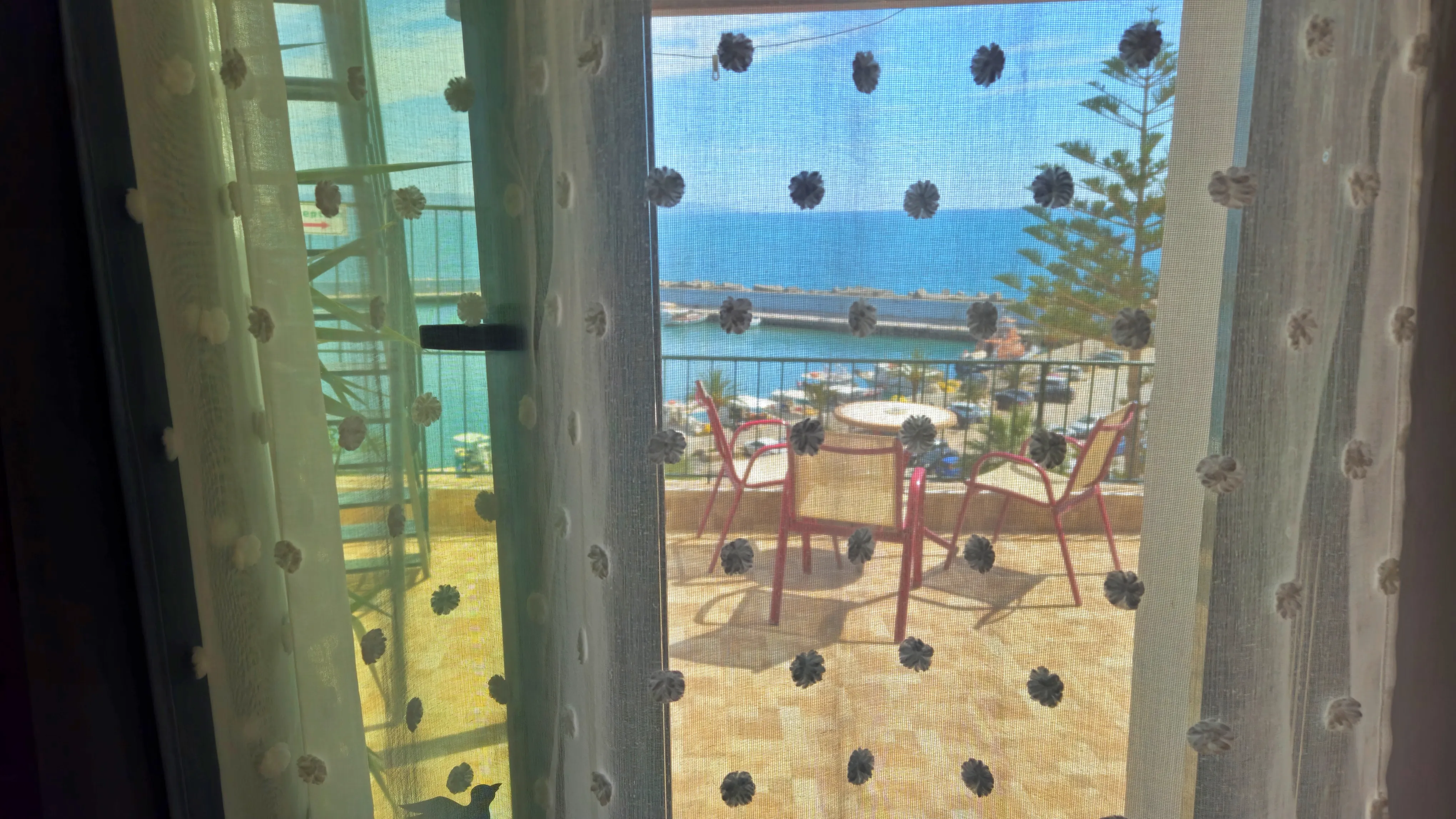 close up view of the window and the view of the sea through a transparent curtain
