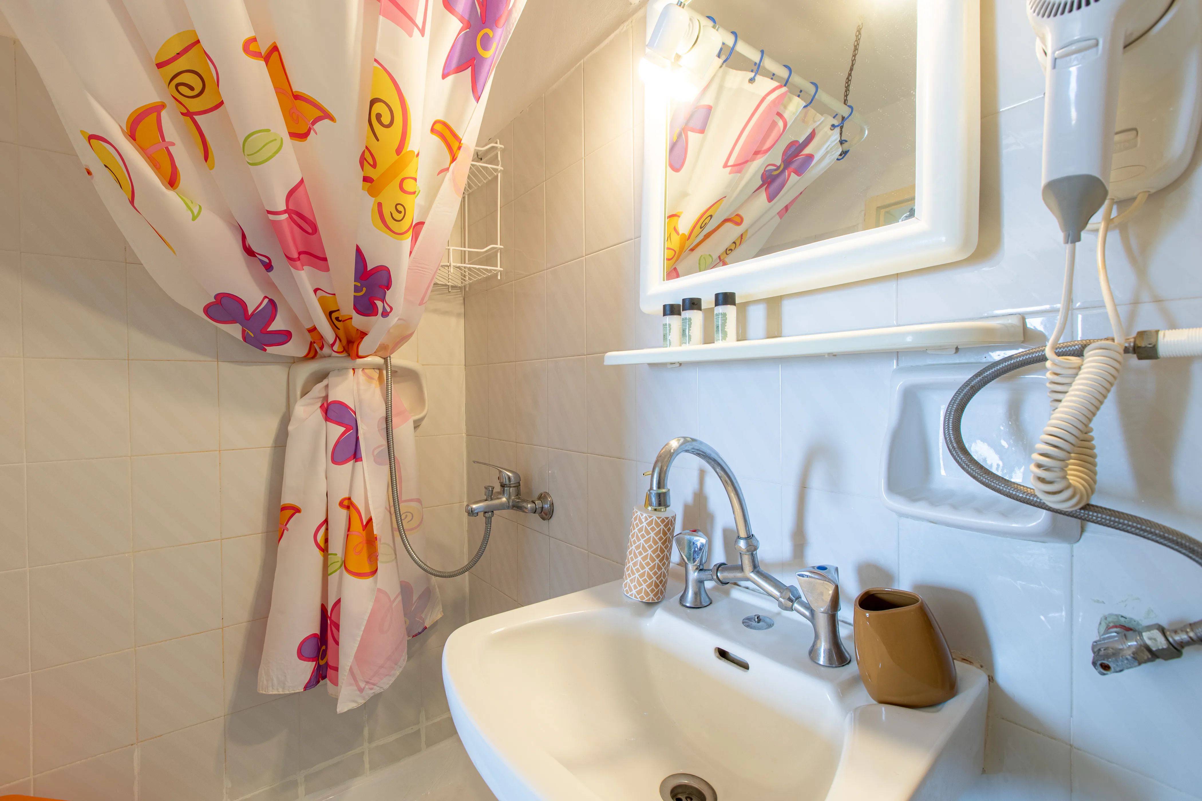 inside view of the bathroom with a white sink and colorful shower curtain